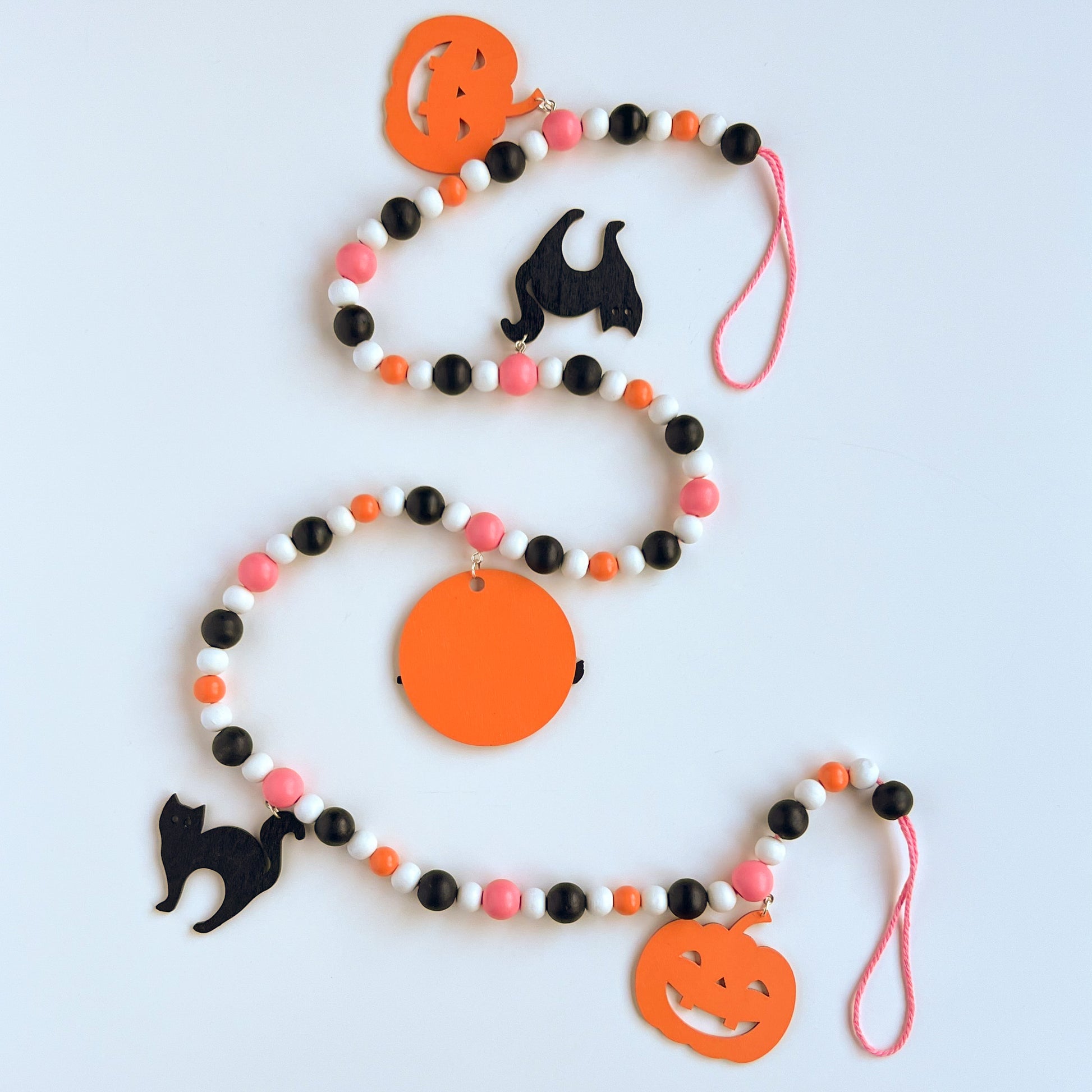 A Bewitching Halloween Handmade Garland. The garland features a witch on a broom, two black cats, and two jack-o-lanterns. Halloween, autumn, fall theme decoration or gift.