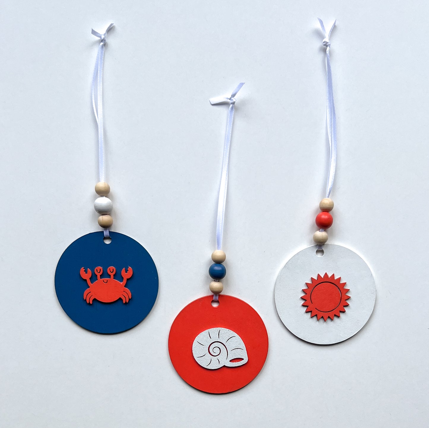 At the Seashore Beachy Set. Three wood ornaments featuring a shell, the sun, or a crab. Summer decor, year-round holiday tree ornament, or gift.
