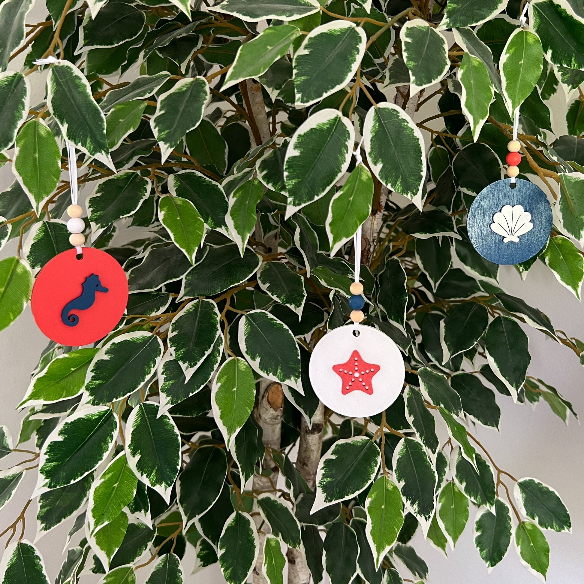At the Seashore Beachy Set. Three wood ornaments featuring a shell, a seahorse, or a starfish. Summer decor, year-round holiday tree ornament, or gift.
