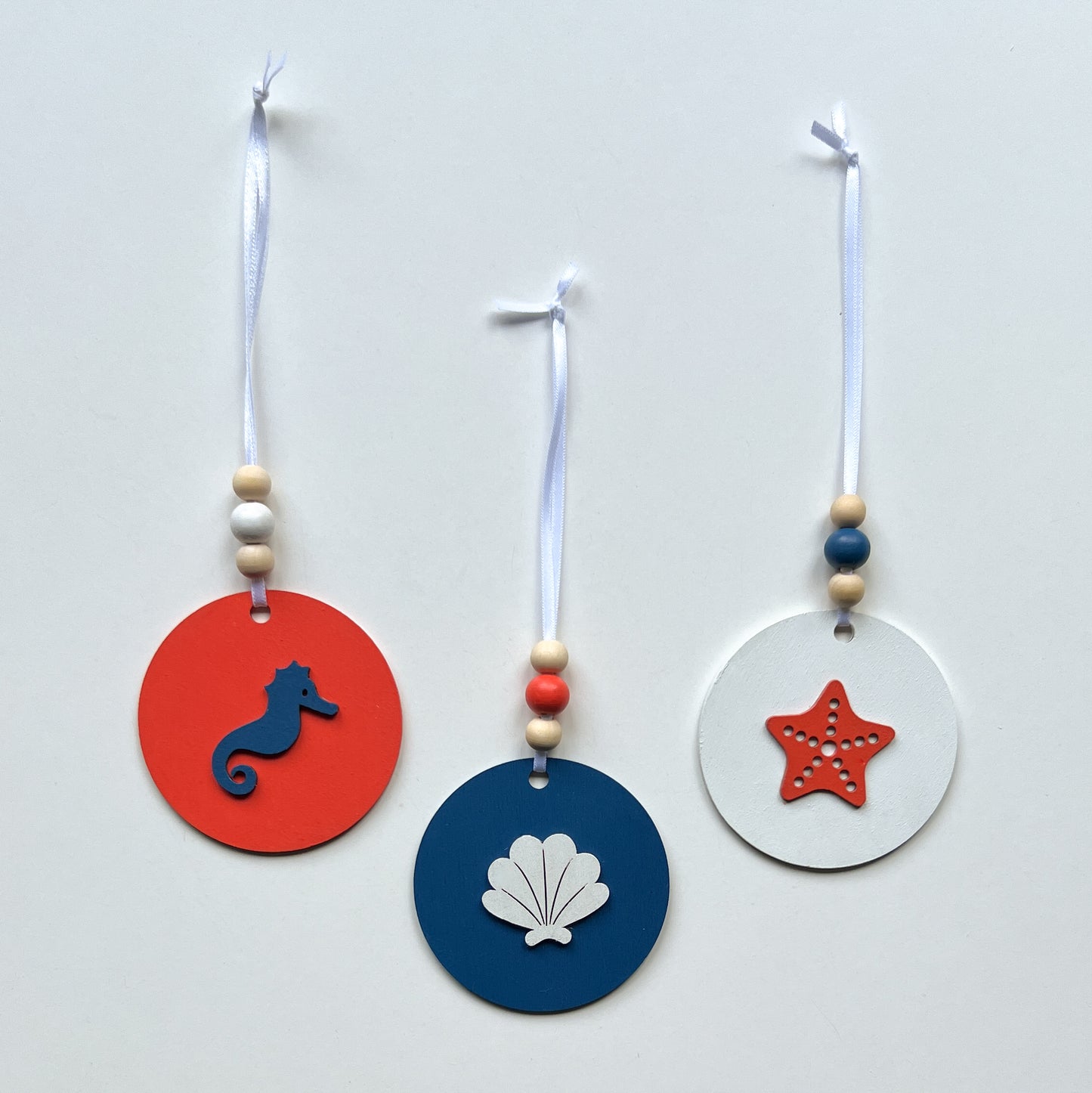 At the Seashore Beachy Set. Three wood ornaments featuring a shell, a seahorse, or a starfish. Summer decor, year-round holiday tree ornament, or gift.
