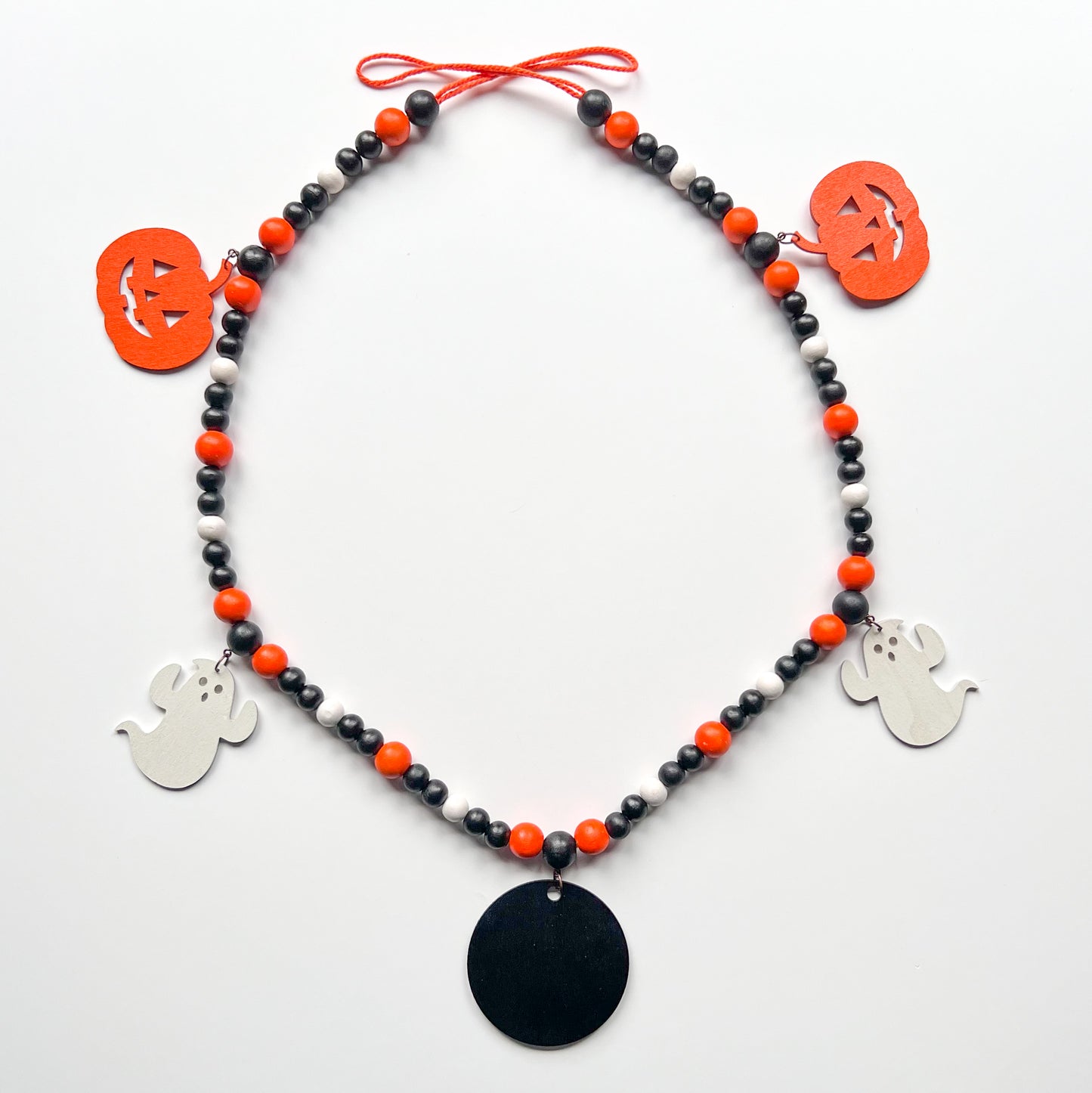 Boo to You Handmade Garland. The garland features five Halloween themed shapes – jack-o-lanterns, ghosts, and a wood boo element in the center. Shapes hang from painted wood beads. Halloween fall seasonal decoration or gift.