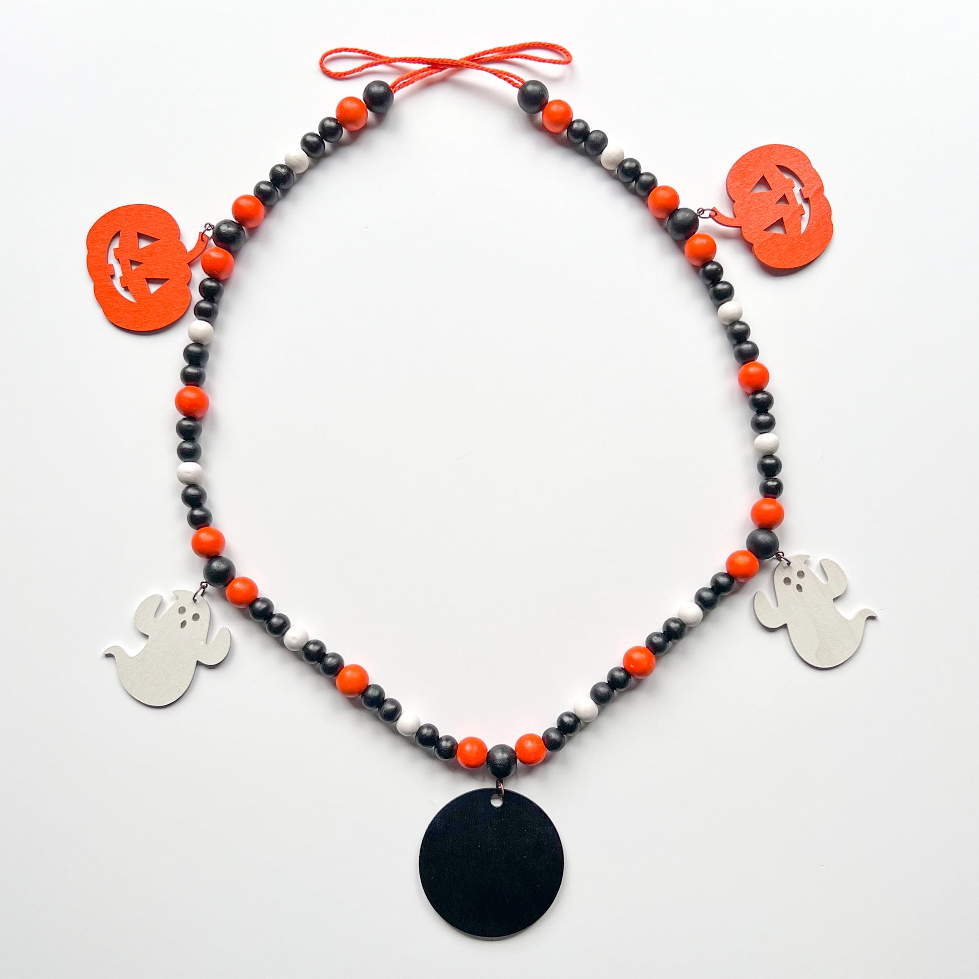 Boo to You Handmade Garland. The garland features five Halloween themed shapes – jack-o-lanterns, ghosts, and a wood boo element in the center. Shapes hang from painted wood beads. Halloween fall seasonal decoration or gift.