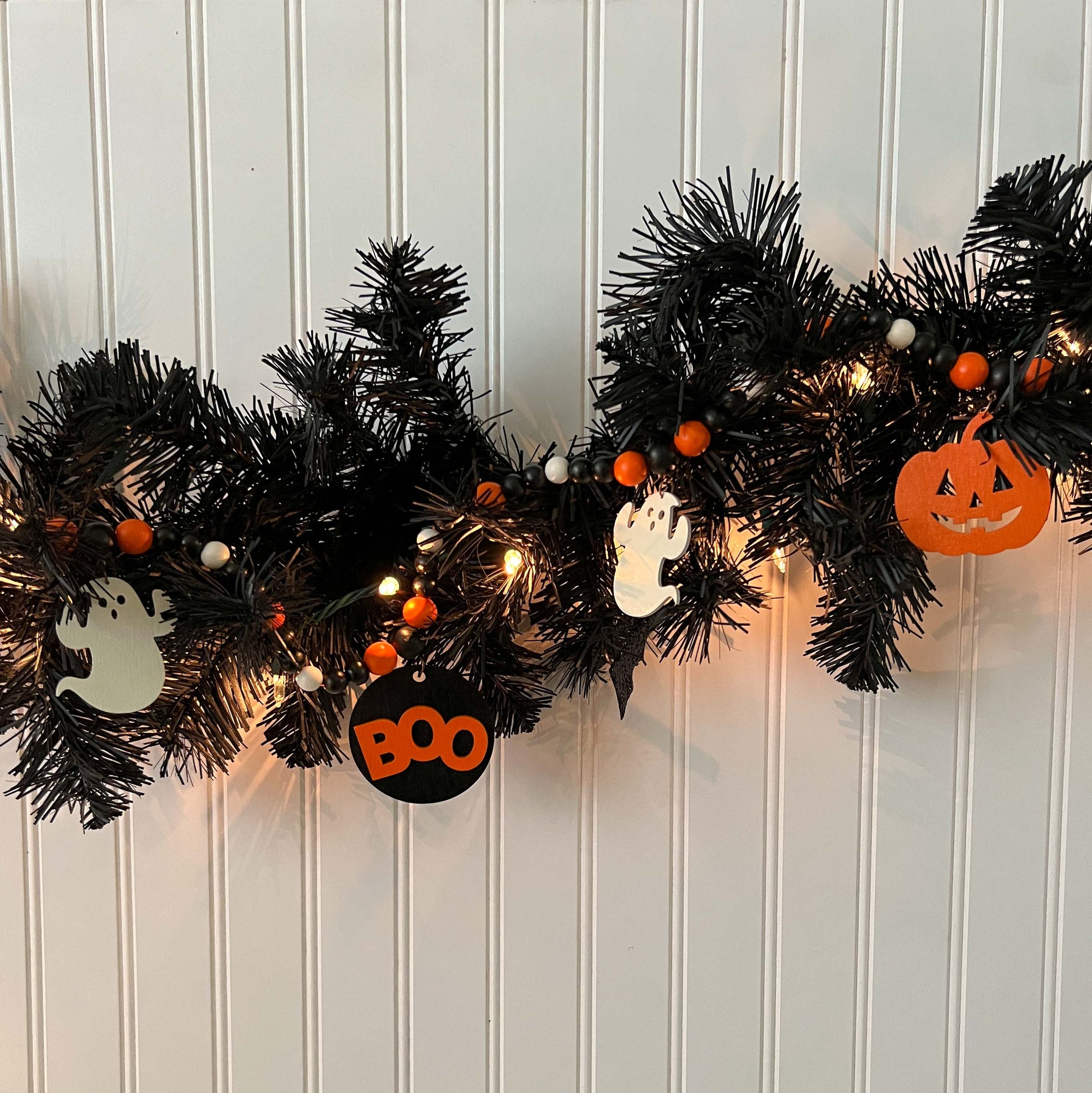 Boo to You Handmade Garland. The garland features five Halloween themed shapes – jack-o-lanterns, ghosts, and a wood boo element in the center. Shapes hang from painted wood beads. Halloween fall seasonal decoration or gift.