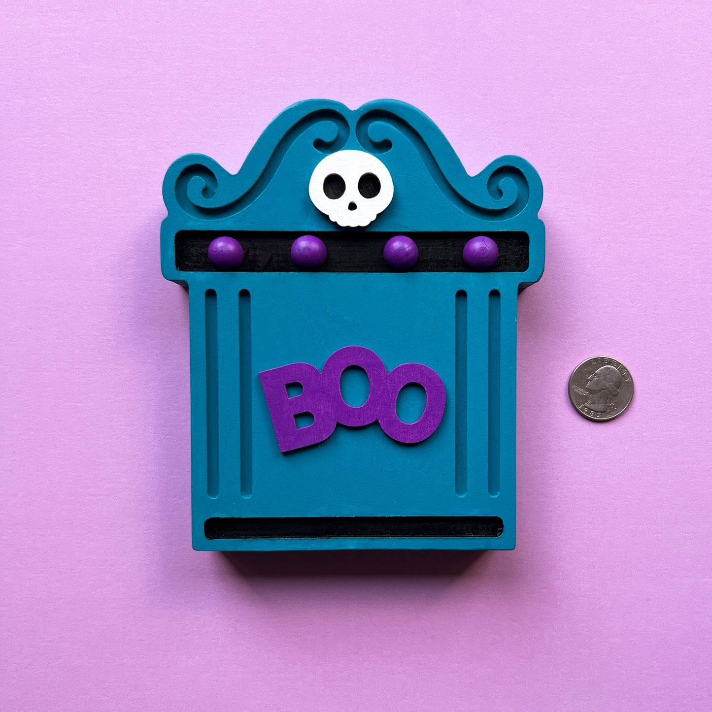 Bright Boo Tombstone Shelf Sitter. Features vibrant colors of blue and purple with a ‘boo’ wood cutout and a little skull. It's free standing, but has a keyhole cutout on the back so can hang on the wall. Halloween decor.