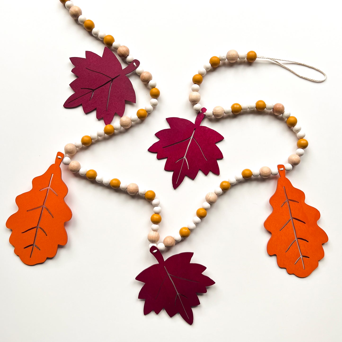 Fall themed wood bead garland with two wood oak leaves and three maple leaves strung with beads.