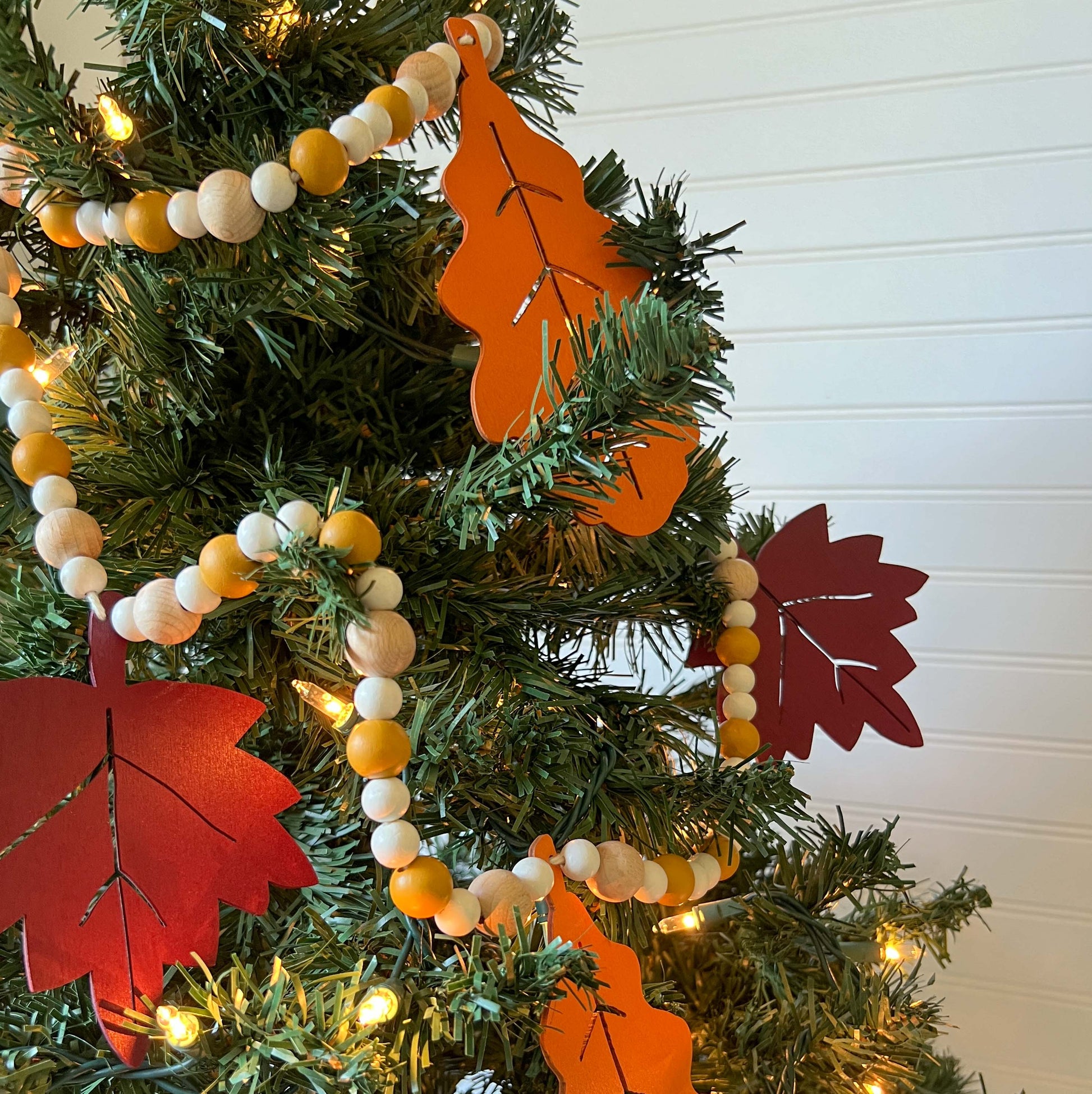 Fall themed wood bead garland with two wood oak leaves and three maple leaves strung with beads.