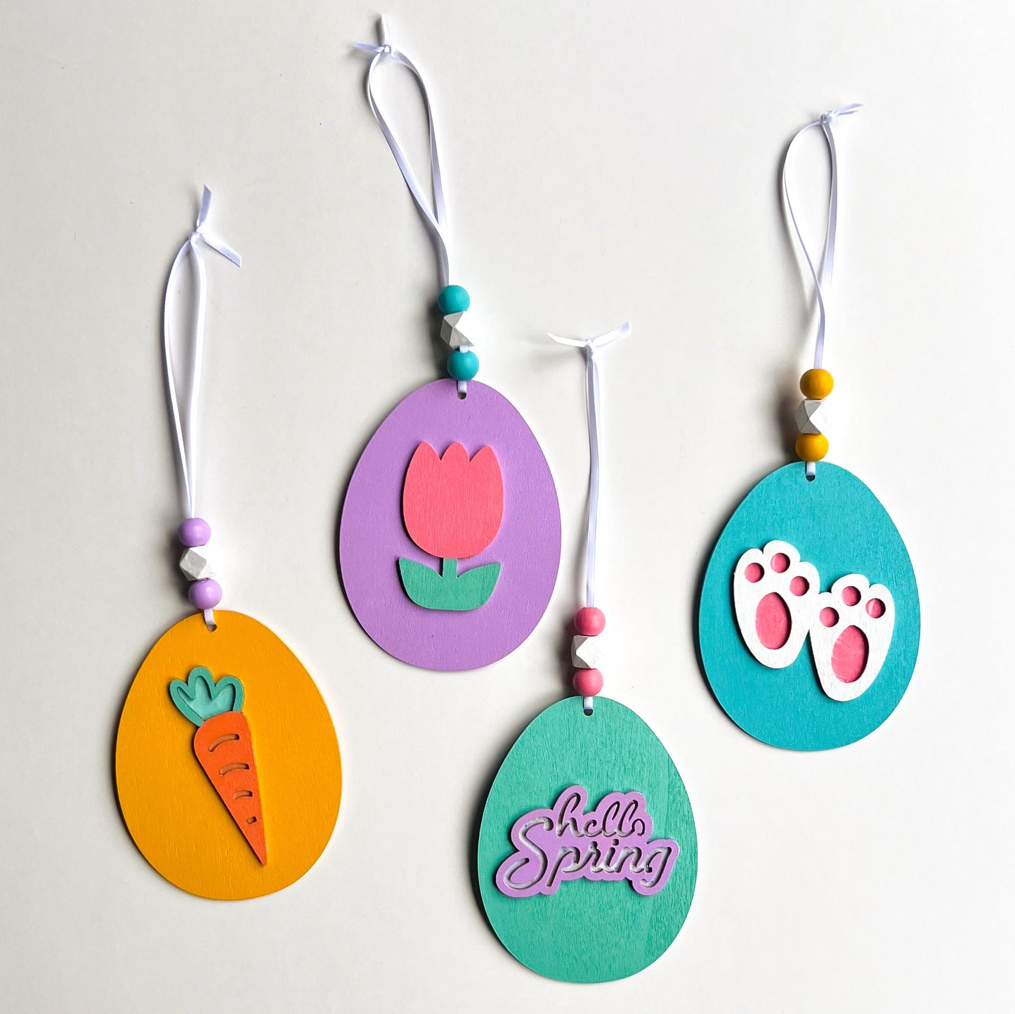 Hello Spring Handmade Ornaments. Flat egg shape ornaments with spring and Easter themed shapes - carrots, flower, rabbit paws. Spring decoration or gift.