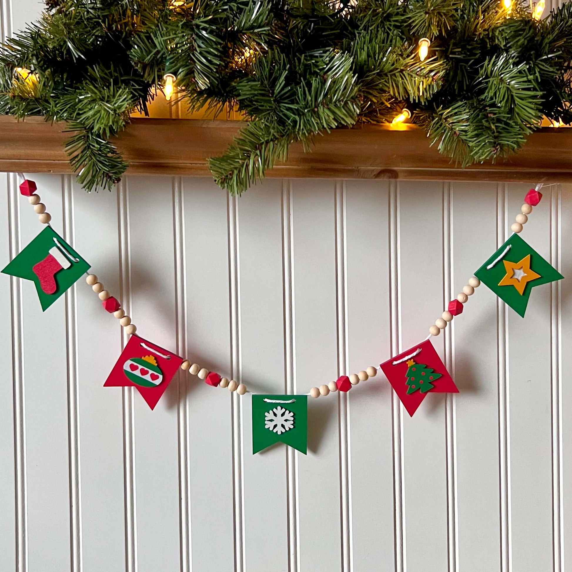 Christmas themed wood bead garland with five wood pennants featuring Christmas themed shapes in red, green, white, and yellow.