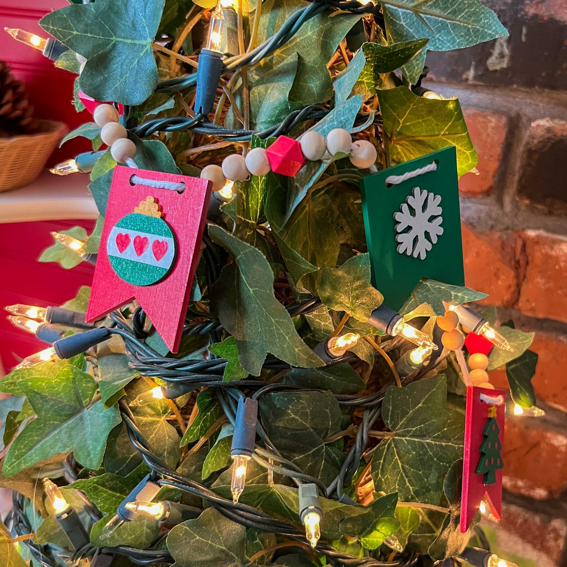 Christmas themed wood bead garland with five wood pennants featuring Christmas themed shapes in red, green, white, and yellow.