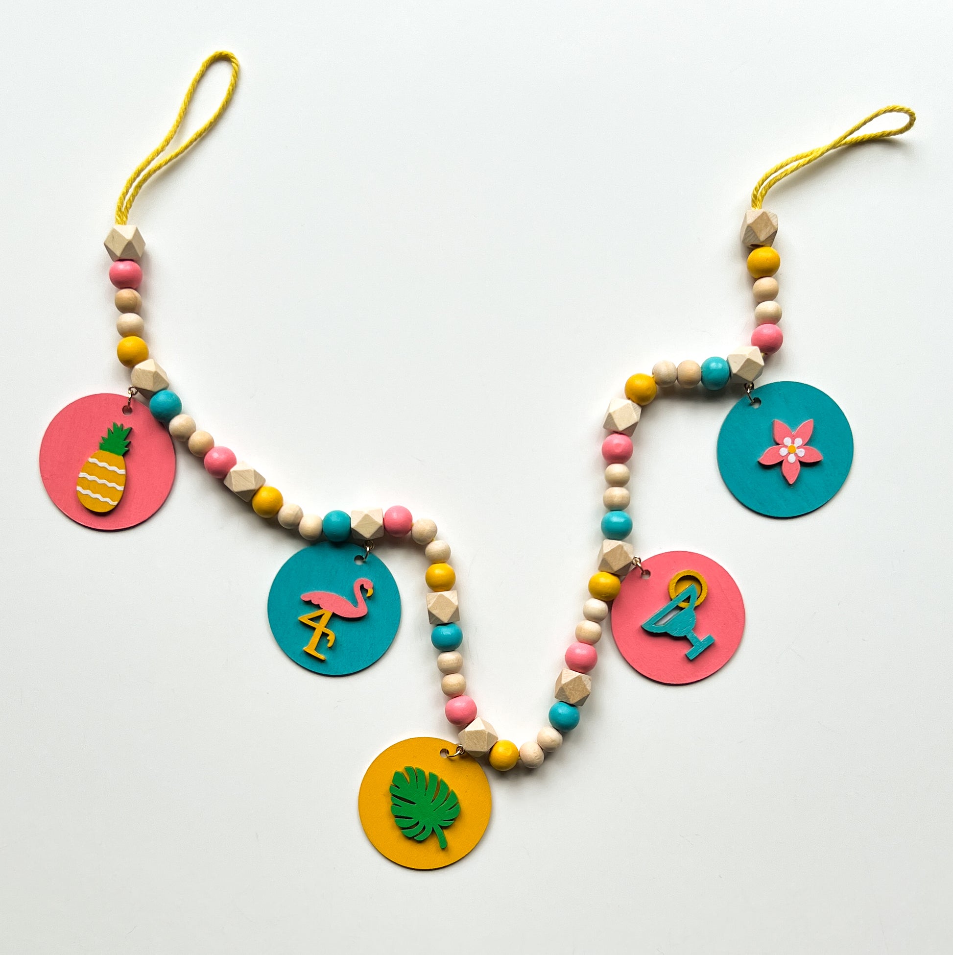 Tropical Little Vacay Mini Garland. Features wood shapes of a pineapple, flamingo, leaf, drink, and flower. Wood bead garland for summer, tropical theme decor or gift.