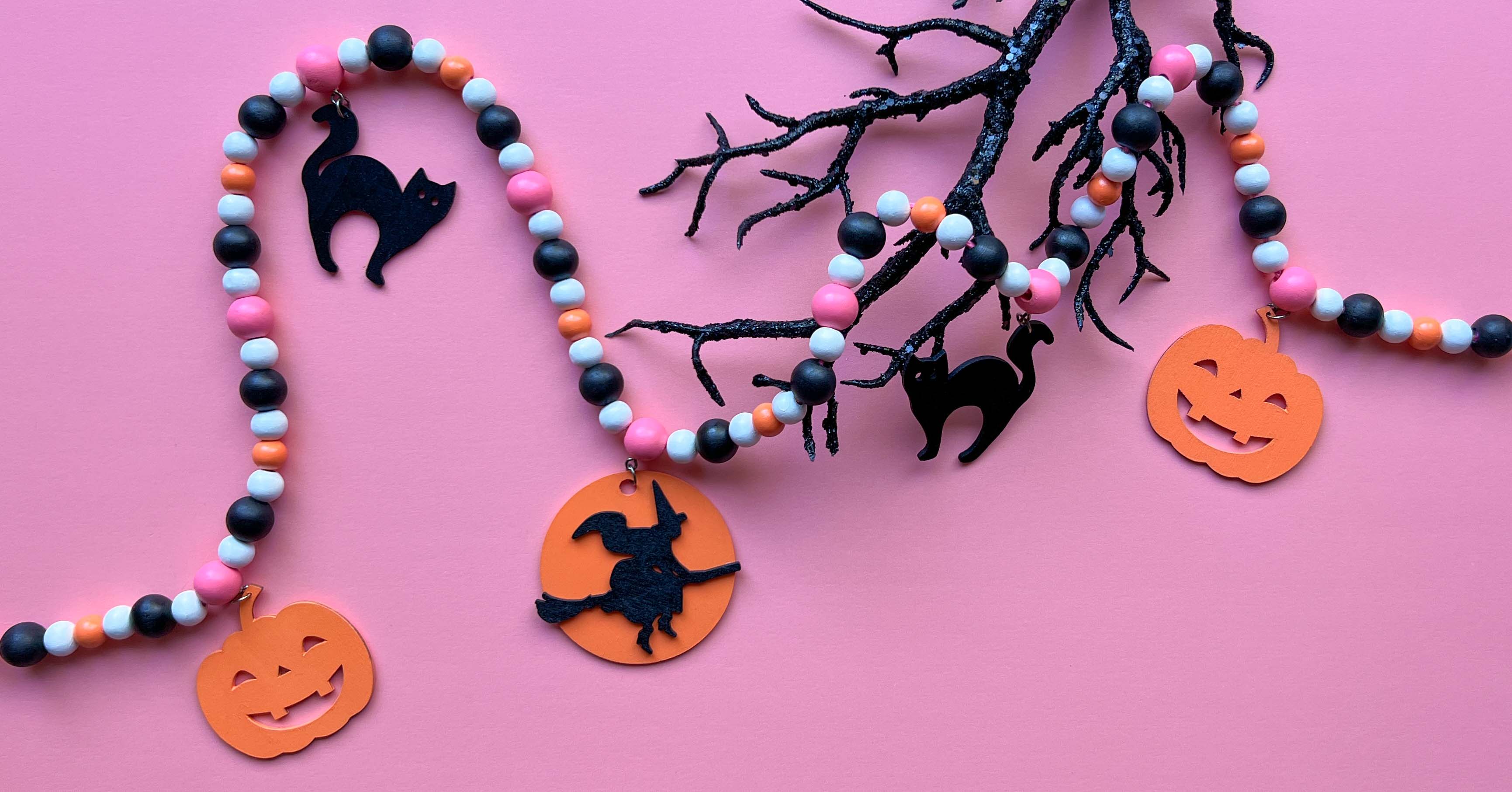 Halloween themed wood bead garland with wood shapes hanging from beads including 2 jack-o-lanterns, 2 black cats, and a witch on a broom.