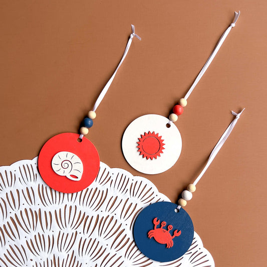 At the Seashore Beachy Set. Three wood ornaments featuring a shell, the sun, or a crab. Summer decor, year-round holiday tree ornament, or gift.