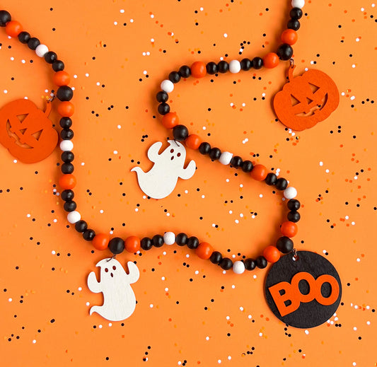 Boo to You Handmade Garland. The garland features five Halloween themed shapes – jack-o-lanterns, ghosts, and a wood boo element in the center. Shapes hang from painted wood beads. Halloween fall seasonal decoration or gift.