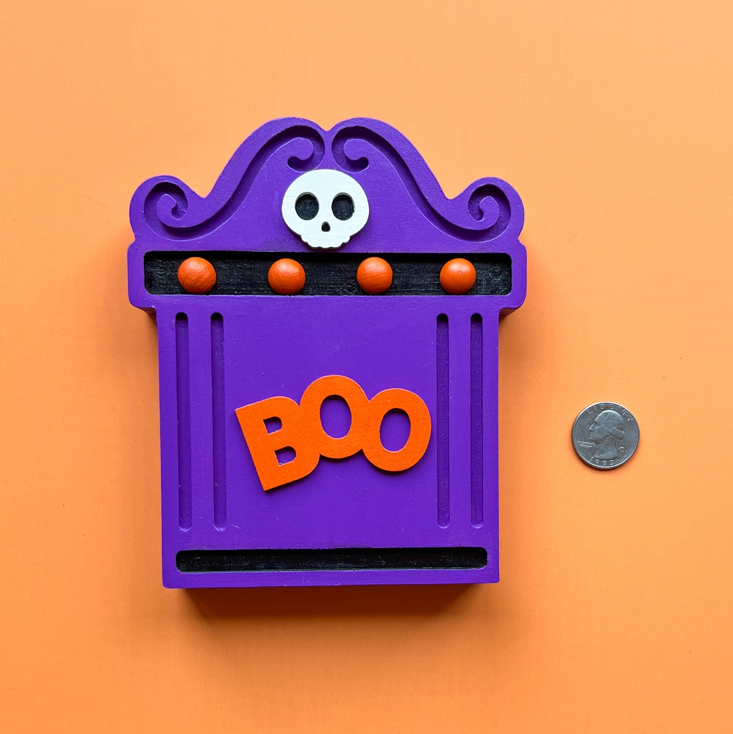 Bright Boo Tombstone Shelf Sitter. Features vibrant colors of purple and orange with a ‘boo’ wood cutout and a little skull. It is free standing, but has a keyhole cutout on the back so can hang on the wall. Halloween decor.