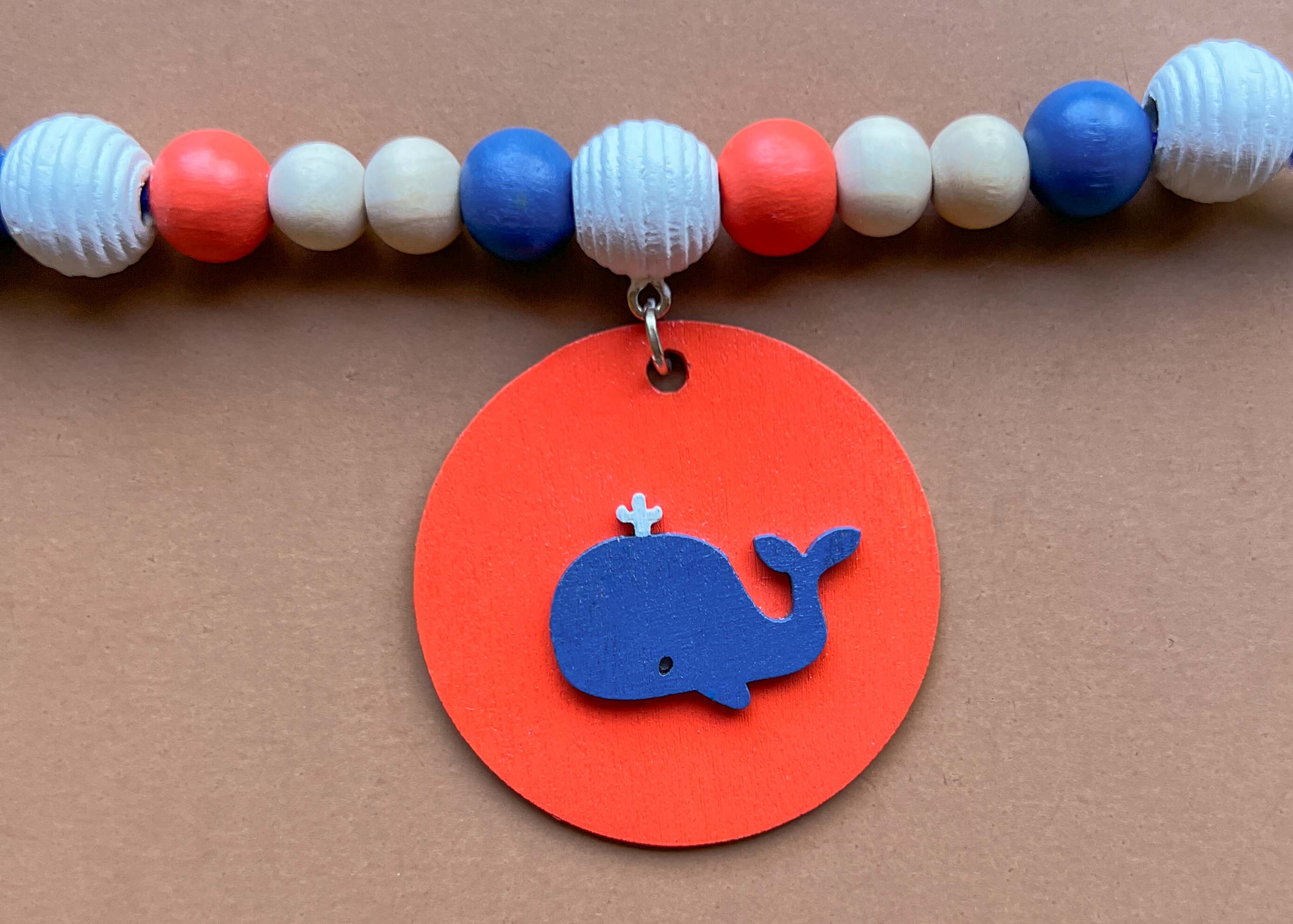 Close up of small wood bead garland featuring a wood element with a small blue whale.