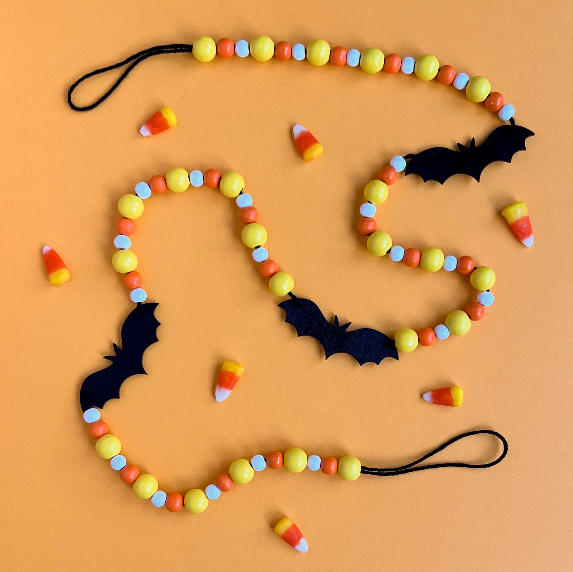 Candy Bats Handmade Garland. The garland features three black bats strung with wood beads in candy corn colors. Halloween, autumn, fall theme decoration or gift.