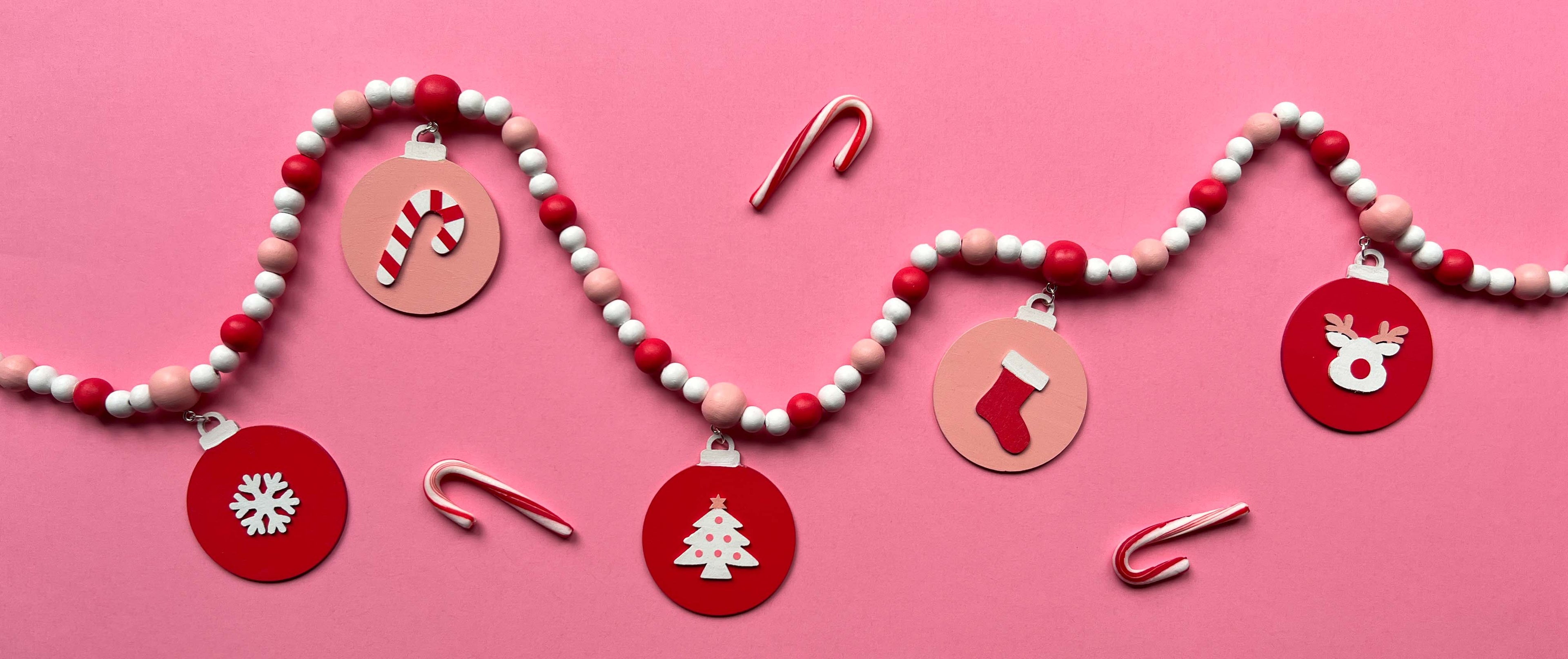 Candy cane colored holiday wood bead garland. Features five wood circles hanging from painted beads with holiday icons.