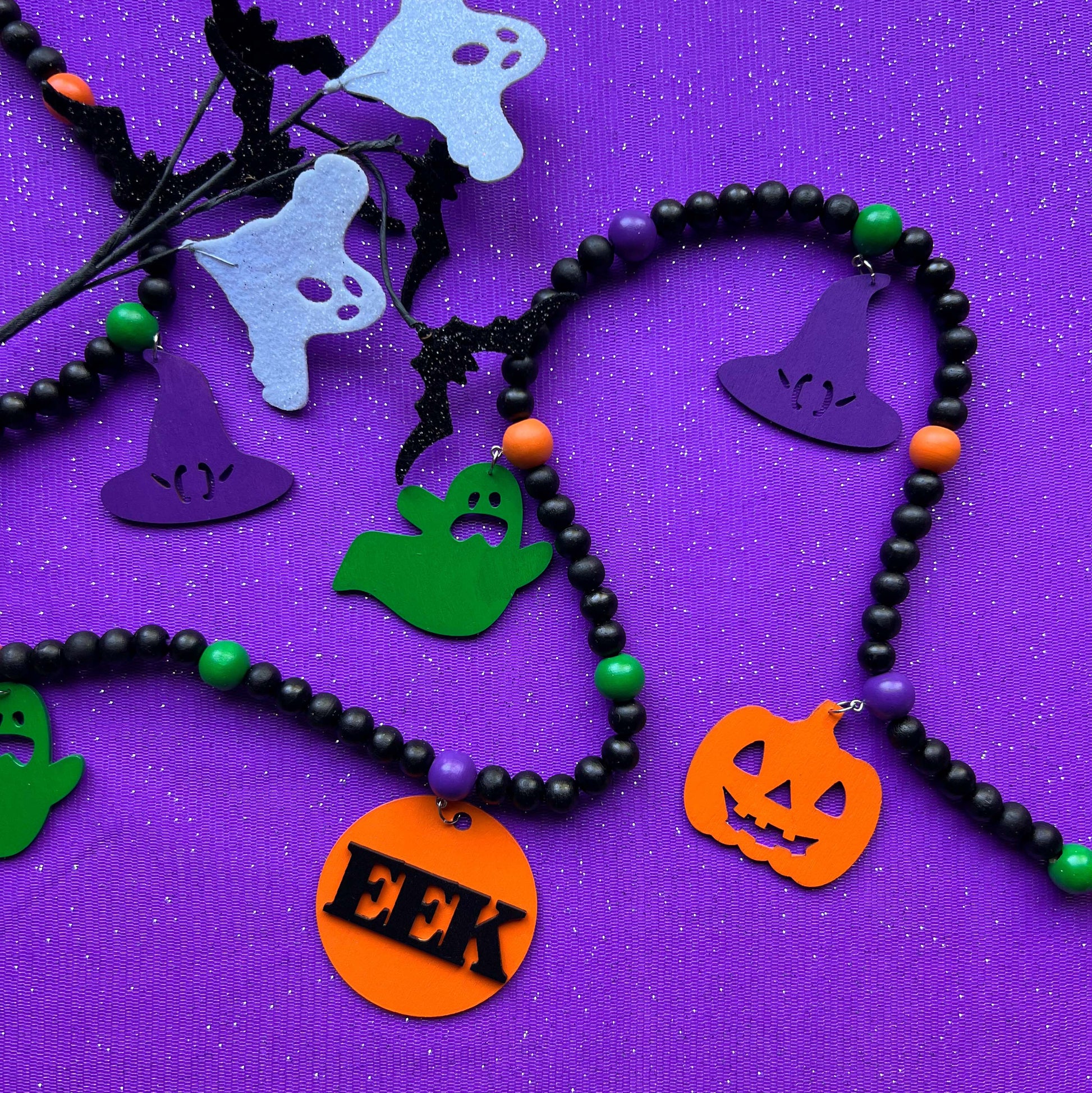 Eek! It’s Halloween Handmade Garland. The garland features seven Halloween themed shapes - pumpkins, ghosts, and witches’ hats. Shapes hang from painted wood beads. Halloween fall seasonal decoration or gift.