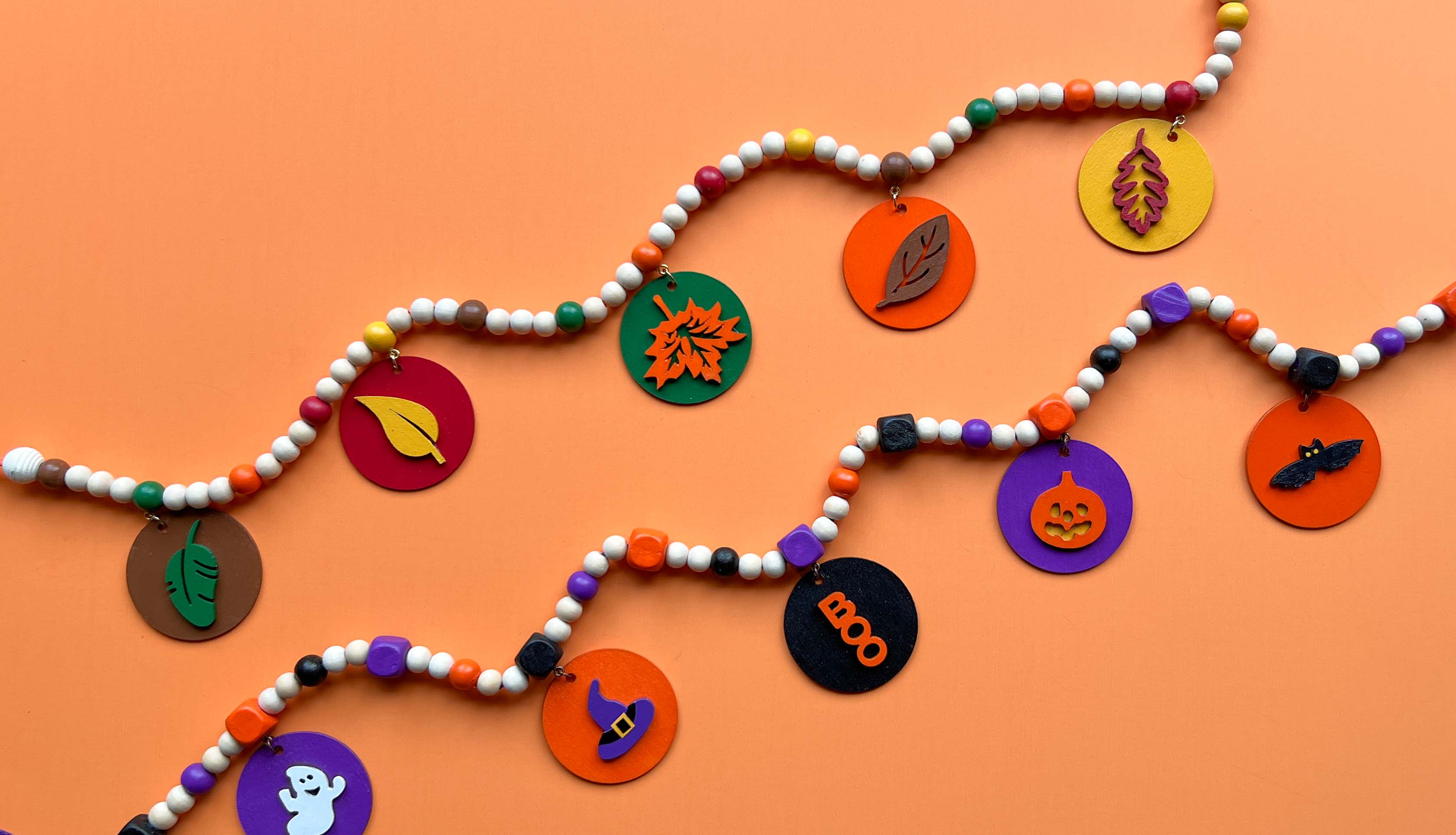 Image of two small wood bead garlands, one themed for fall and the other for Halloween.