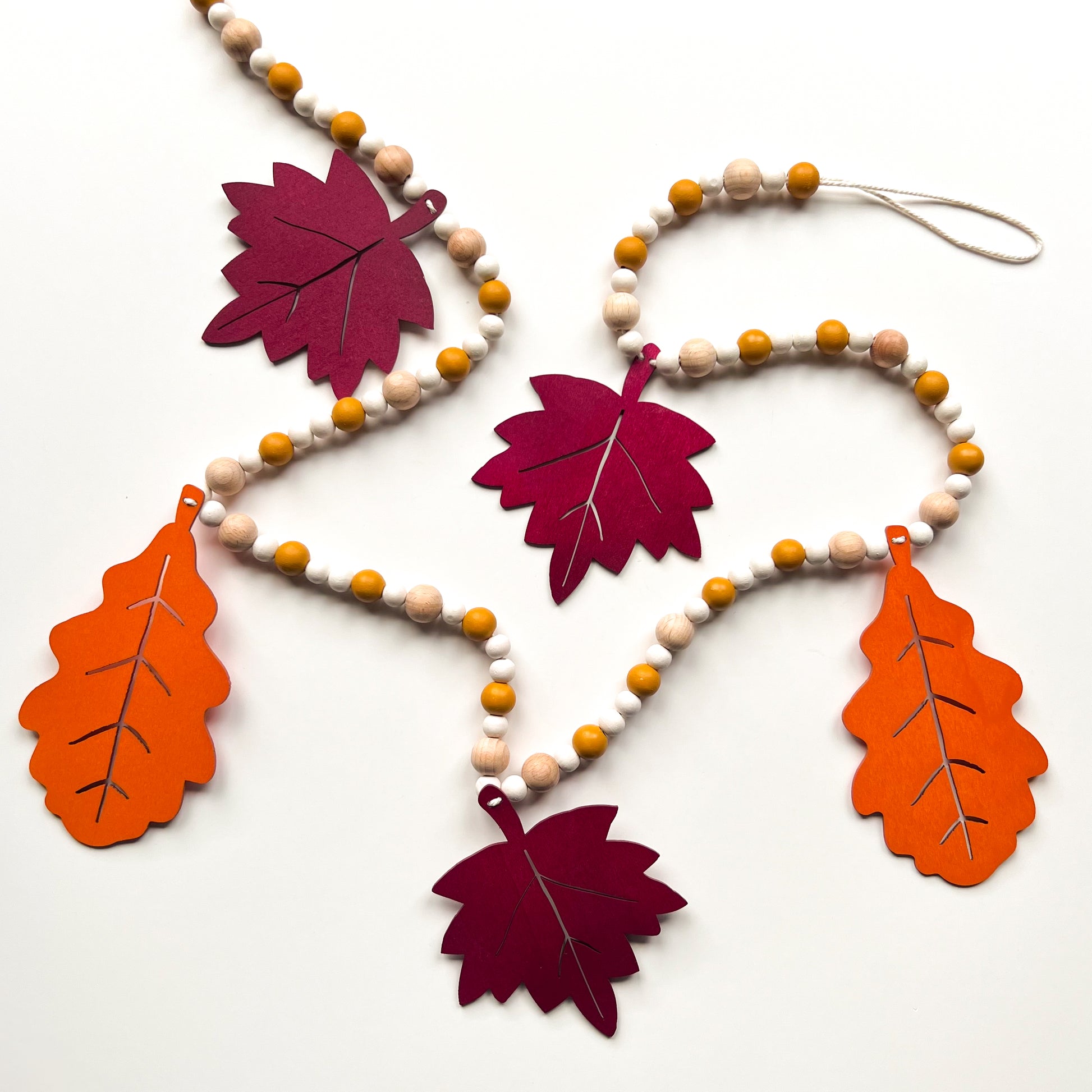 Fall themed wood bead garland with two wood oak leaves and three maple leaves strung with beads. 