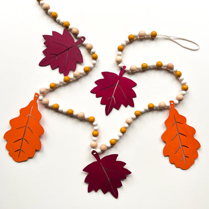 Fall themed wood bead garland with two wood oak leaves and three maple leaves strung with beads. 