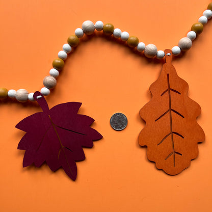 Fall themed wood bead garland with two wood oak leaves and three maple leaves strung with beads. 