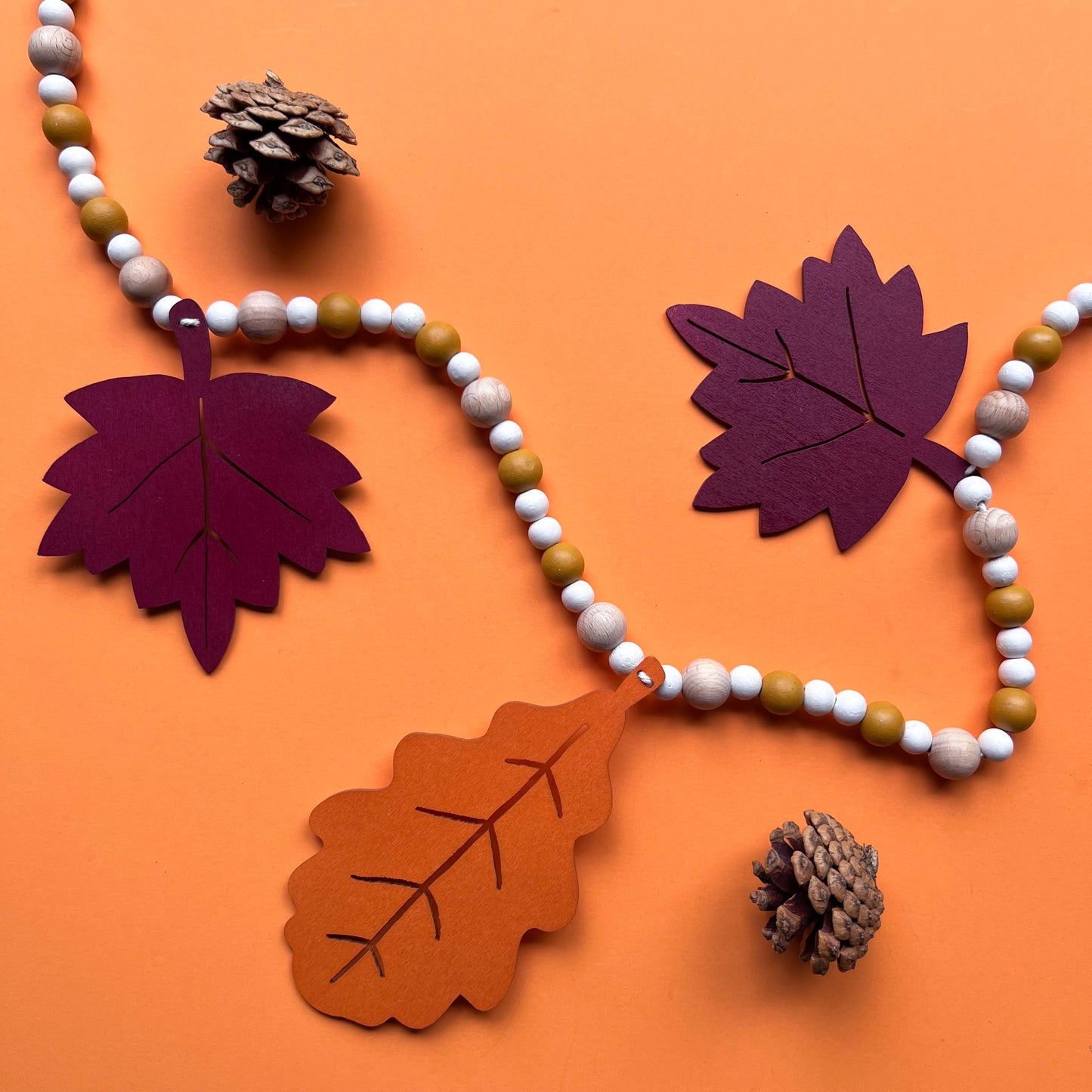 Fall themed wood bead garland with two wood oak leaves and three maple leaves strung with beads. 