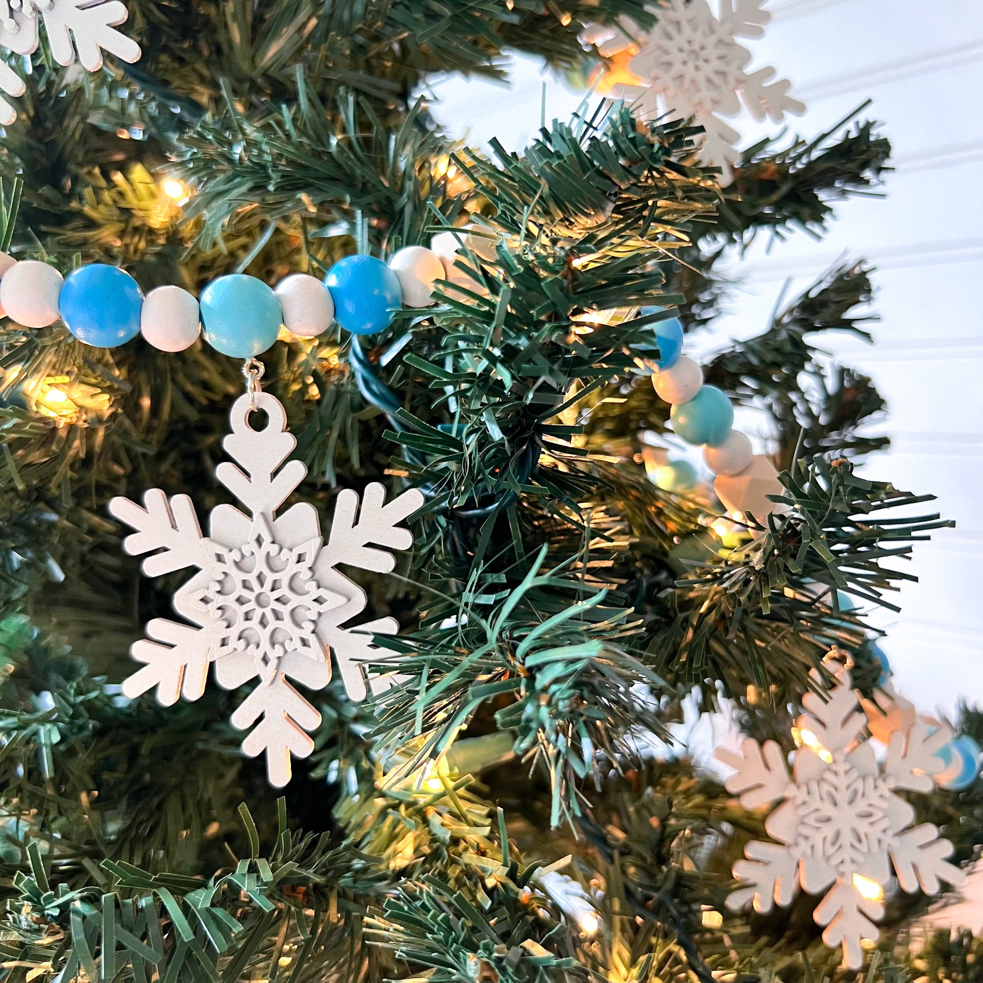 Falling Snowflakes Handmade Garland. The garland features five unique wood snowflakes that hang from painted wood beads. Christmas holiday winter seasonal decoration or gift.