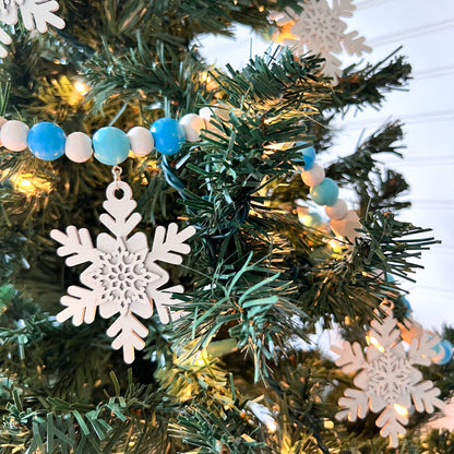 Falling Snowflakes Handmade Garland. The garland features five unique wood snowflakes that hang from painted wood beads. Christmas holiday winter seasonal decoration or gift.