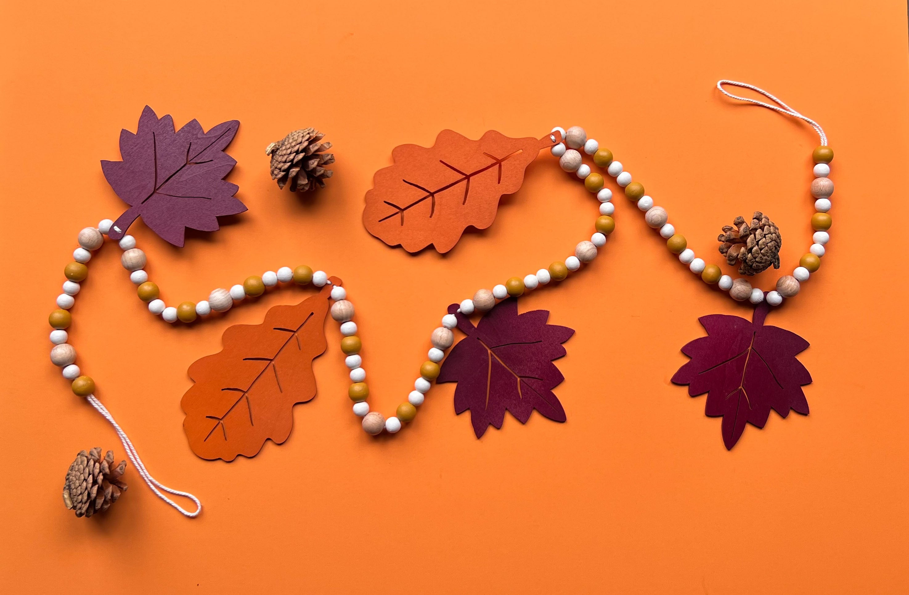 Handmade wood bead garland with five large painted wood leaves, oak and maple, strung in line with beads.