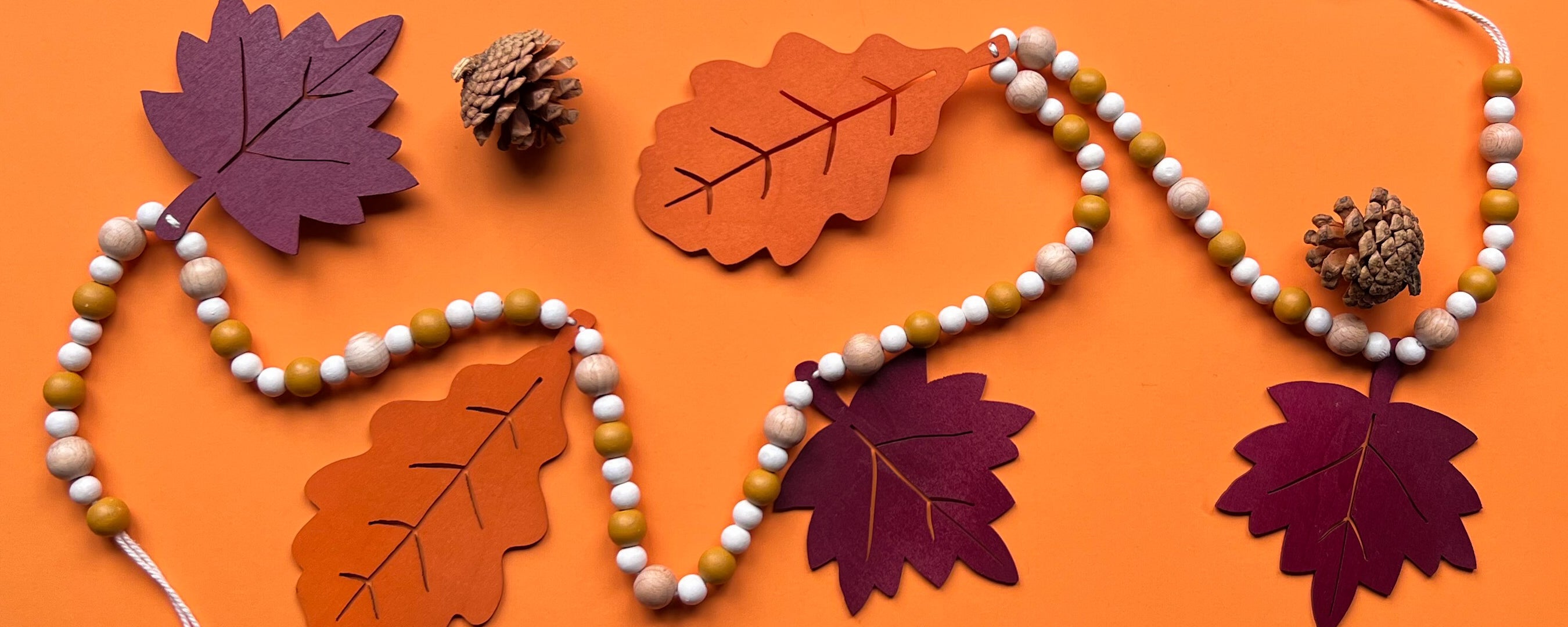 Fall themed wood bead garland with two wood oak leaves and three maple leaves strung with beads. 