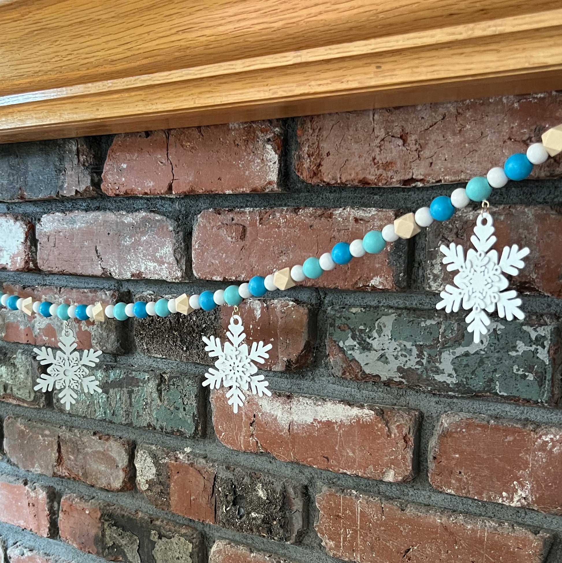 Falling Snowflakes Handmade Garland. The garland features five unique wood snowflakes that hang from painted wood beads. Christmas holiday winter seasonal decoration or gift.