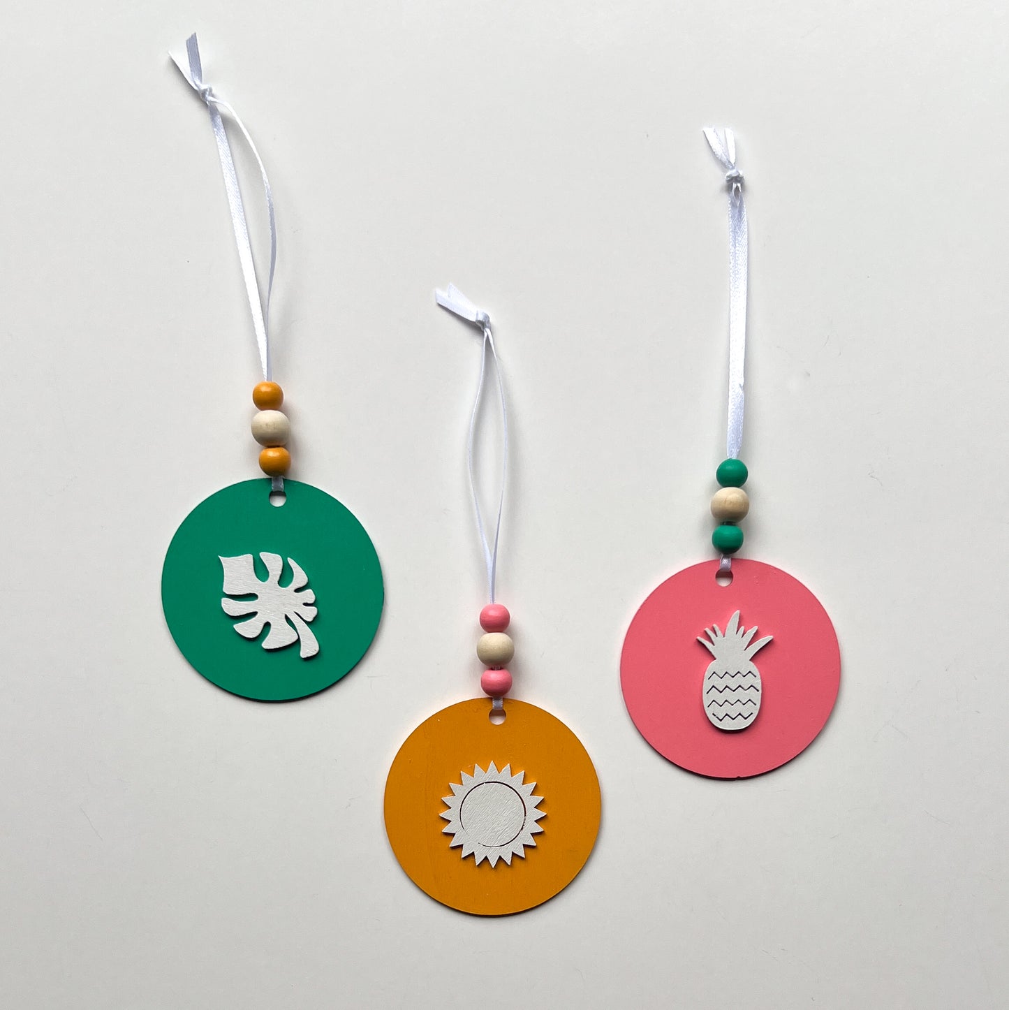 Fun in the Sun Tropical Ornament Set of 3. Wood ornaments featuring a monstera leaf, pineapple, or sun. Seasonal summer decor; year-round holiday tree ornament.