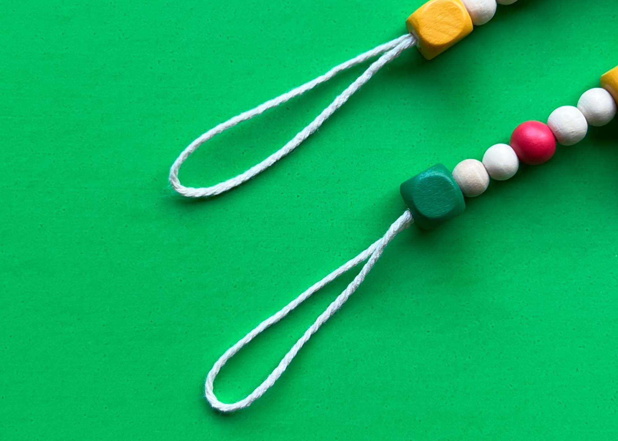 Close up of end loops on a wood bead garland, featuring white macrame cord.