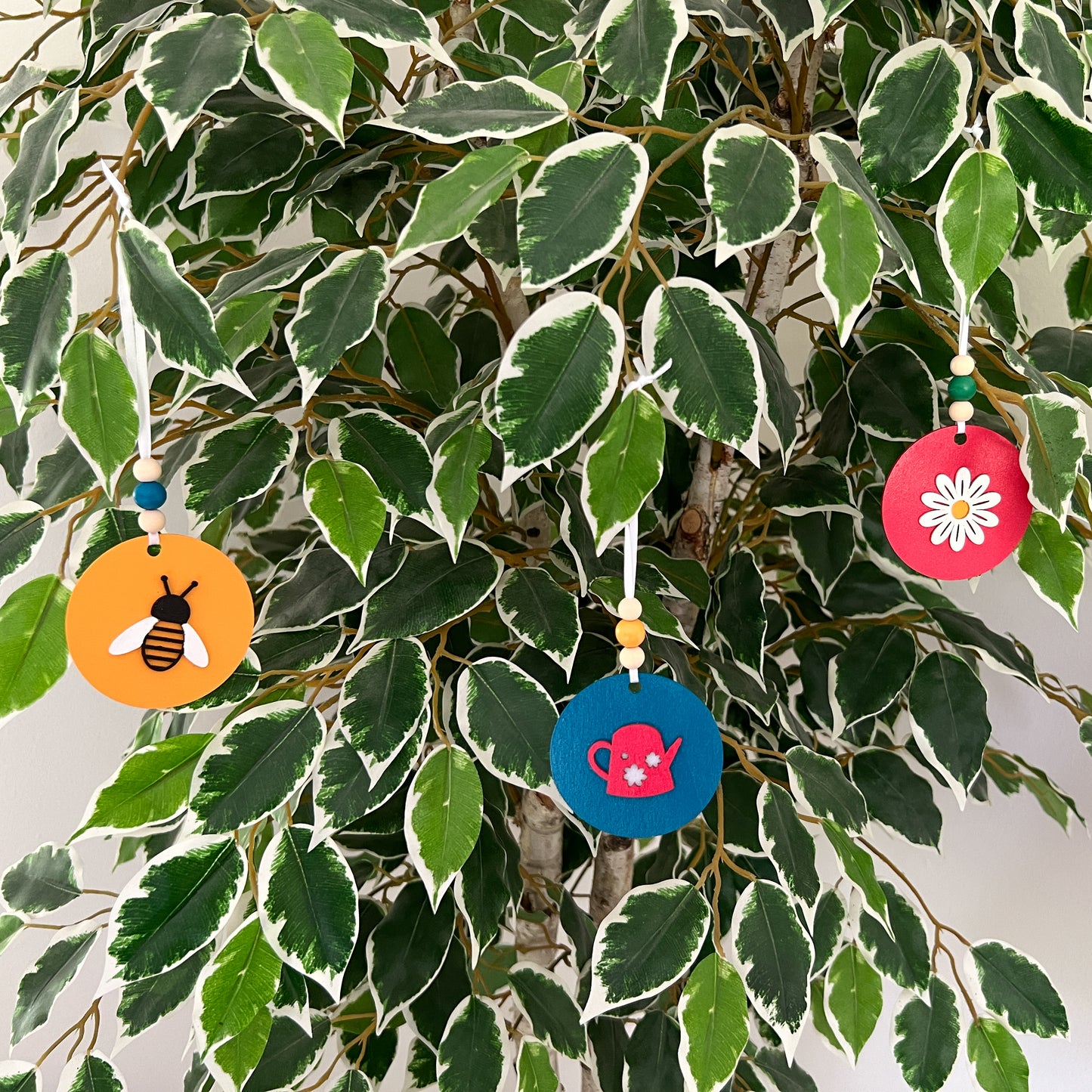 In the Garden Ornament Set. Three ornaments featuring a watering can, a daisy flower, and a bumblebee. Year-round holiday tree, spring decor or gift.