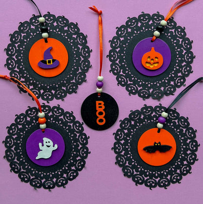 Set of 5 small wood Halloween ornaments. Feature 2 inch wood circles with Halloween themed shapes. Include three wood beads with a ribbon.