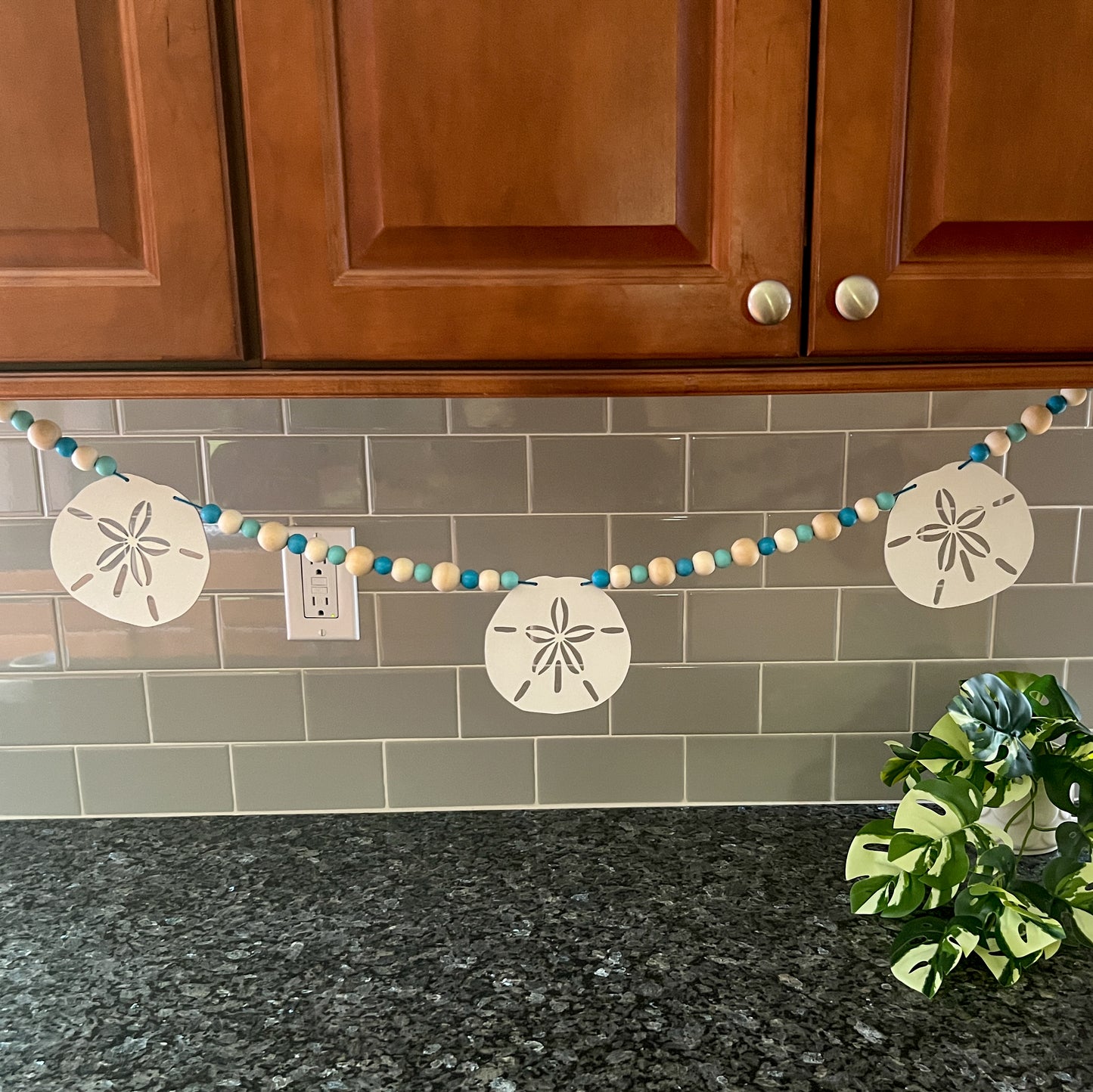 Seaside Sand Dollars Handmade Garland. The garland features three white sand dollars with blue and natural wood beads. Summer, ocean, beach theme decoration or gift.