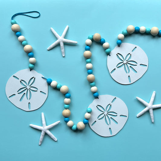 Seaside Sand Dollars Handmade Garland. The garland features three white sand dollars with blue and natural wood beads. Summer, ocean, beach theme decoration or gift.