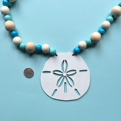 Seaside Sand Dollars Handmade Garland. The garland features three white sand dollars with blue and natural wood beads. Summer, ocean, beach theme decoration or gift.